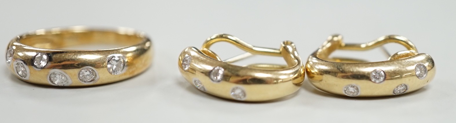 A modern 14k and gypsy set six stone diamond band, size N and a pair of matching earrings, gross weight 8.1 grams.